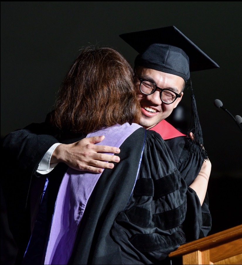 Dr. Jimmy Wei at graduation, embracing a mentor on stage.
