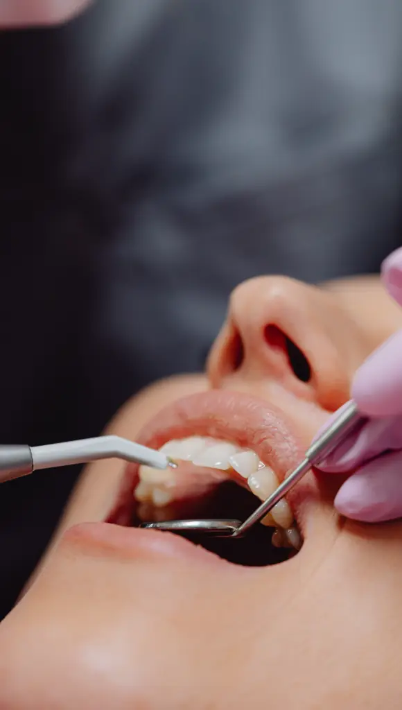 A dental exam in progress, with a mirror and instruments at the front teeth.
